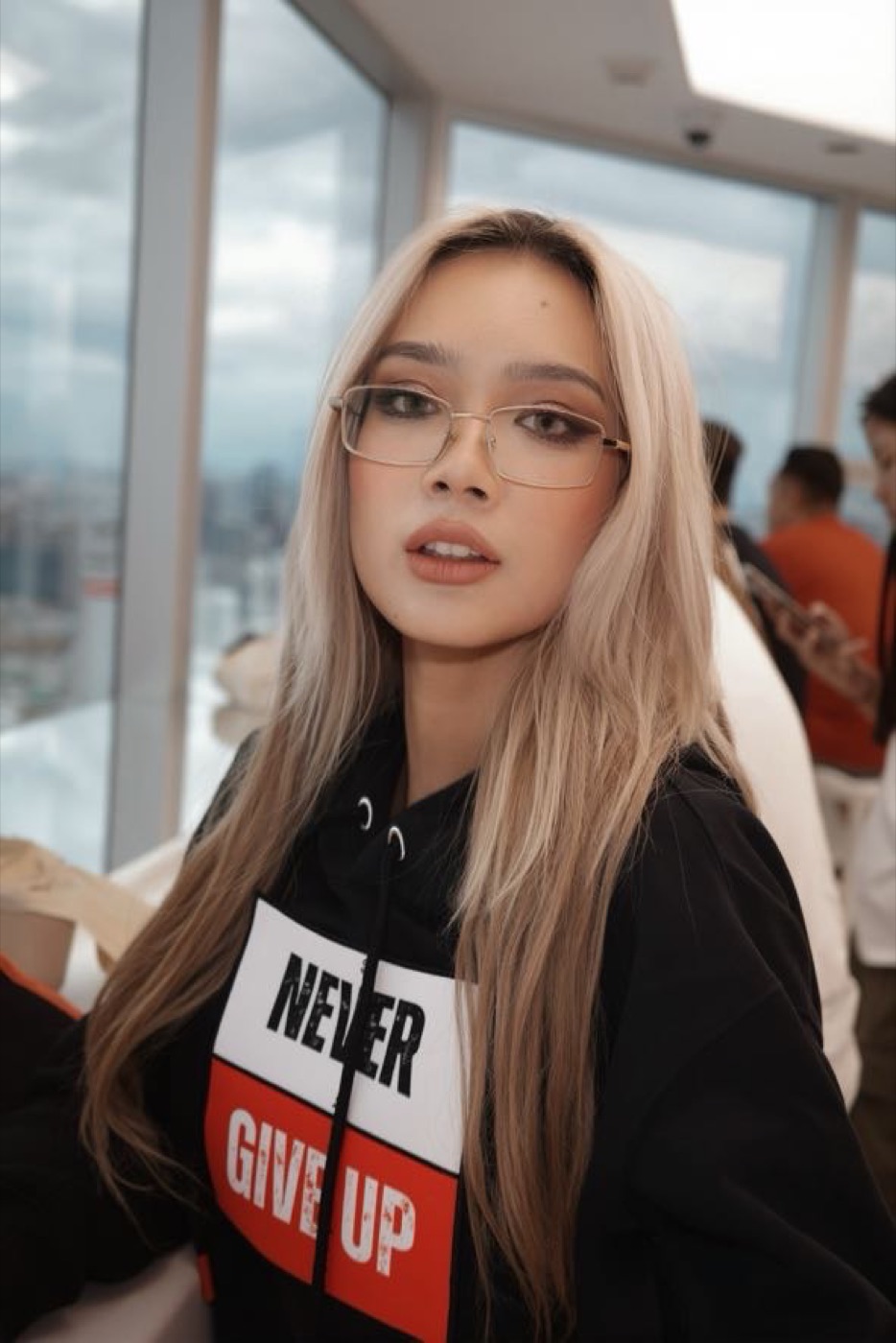 Close-up of the model in the Never Give Up hoodie on a rooftop observation deck