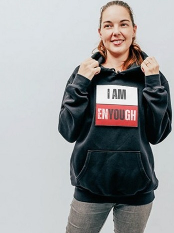 Madeleine Lemke, co-founder of ENYOUGH, smiling in the I Am Enyough hoodie