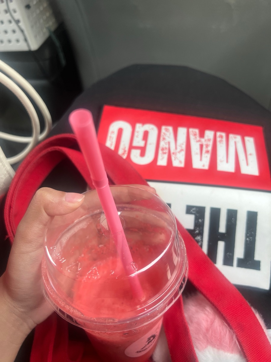 Close-up of the model holding a smoothie beside The Big Mango Signal Tote