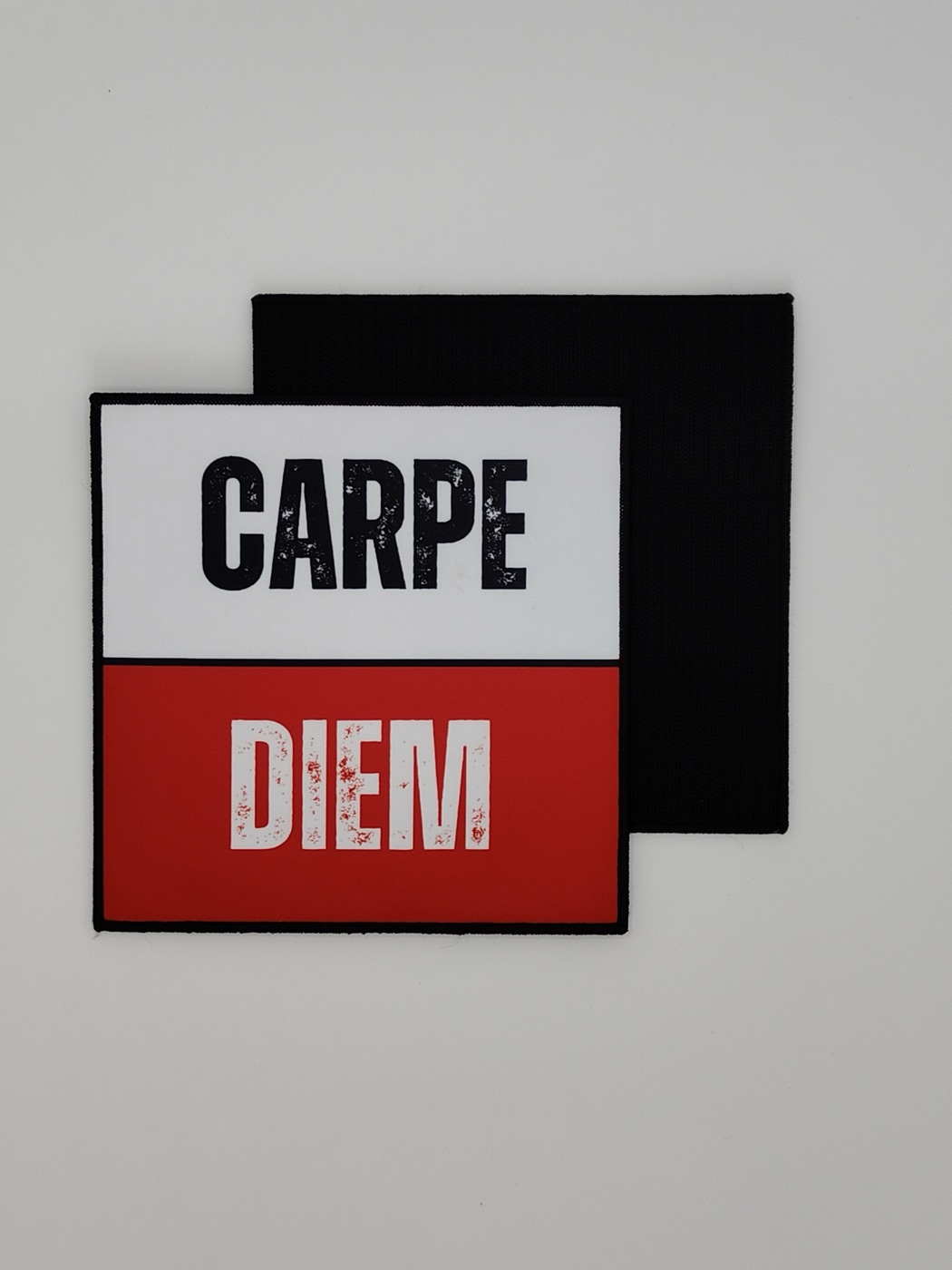A real Carpe Diem patch photographed face-up next to its hook-and-loop backing