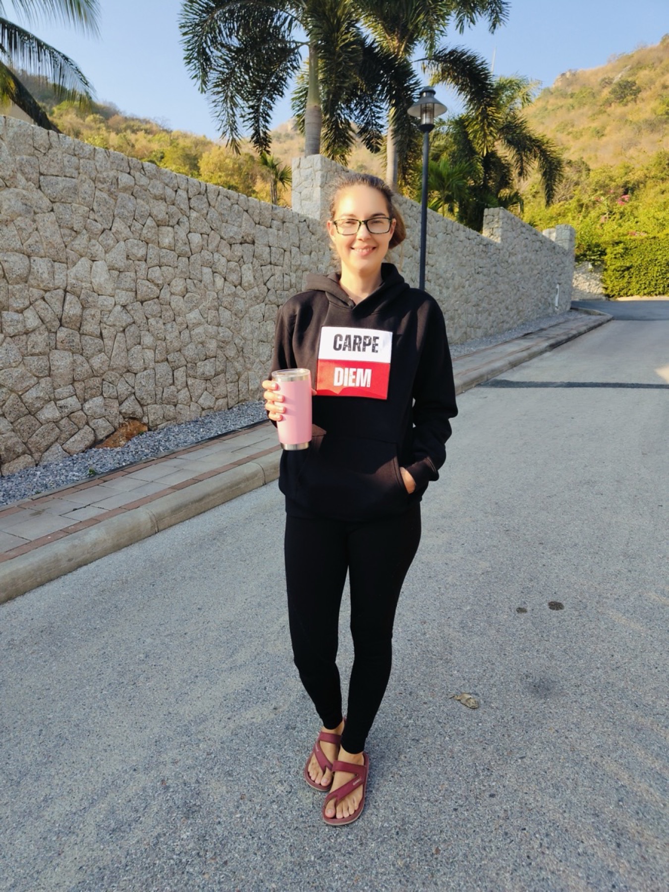 Madeleine Lemke, co-founder of ENYOUGH, wearing the Carpe Diem hoodie on a quiet road outside Bangkok